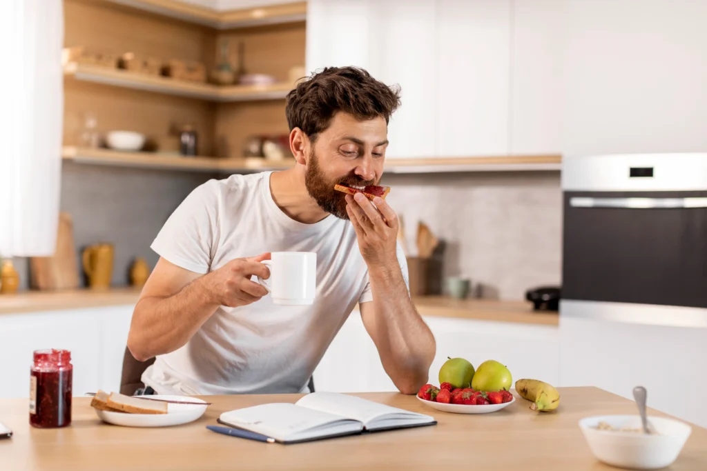 busy-handsome-adult-caucasian-male-white-tshirt-eats-sandwich-with-jam-drinks-coffee-reads-book