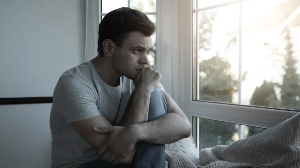 depressed-sad-frustrated-crying-scared-instability-mental-bipolar-young-man-sitting-windowsill-home-headache-because-overworked-stress-men-health-magazine img