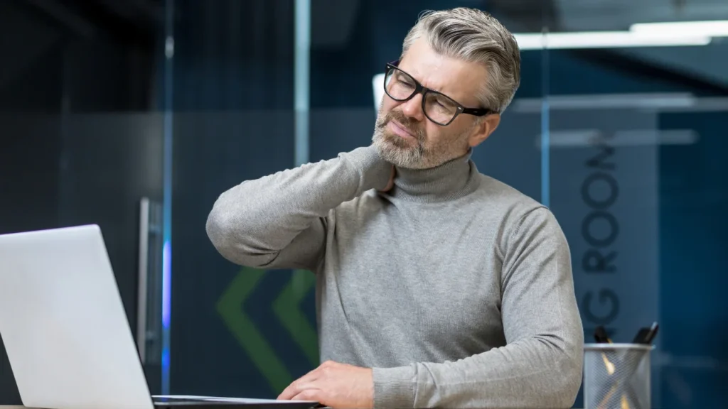 Senior mature businessman massaging neck at office, tired and stressed.